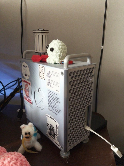 Auto-generated description: A computer case is decorated with stickers and three small plush toys on top.